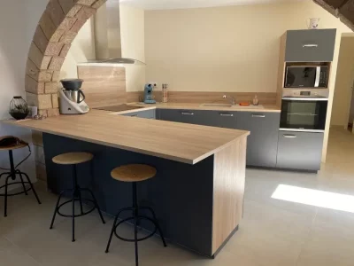 Cuisine grise sur mesure, située sous une magnifique voûte en pierre. L'association du gris moderne avec le bois chaleureux crée un contraste harmonieux, tandis que la voûte en pierre ajoute une touche d'authenticité et de caractère à l'espace.