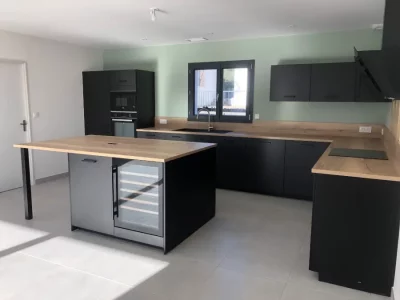 Cuisine sur mesure noire mate avec un plan de travail en bois clair, combinant élégance et chaleur. Le contraste entre le noir profond et le bois clair crée une ambiance contemporaine et accueillante sur Nîmes et Montpellier.