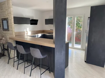 Cuisine sur mesure contemporaine noire avec un plan de travail en bois clair, offrant un contraste élégant. L'association du noir avec le bois clair crée une ambiance moderne et chaleureuse, parfaitement adaptée aux besoins et aux préférences du client sur Nîmes et Montpellier
