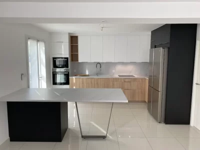 Cuisine sur mesure blanche avec une combinaison d'éléments en bois et d'autres éléments noirs, offrant un contraste subtil et contemporain. L'association du blanc lumineux avec le bois naturel et le noir crée une ambiance équilibrée et élégante sur Nîmes et Montpellier