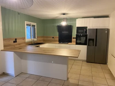 Cuisine blanche avec un plan de travail en bois, offrant une esthétique élégante et chaleureuse. Le contraste entre le blanc lumineux et le bois naturel crée une ambiance contemporaine et accueillante par L. Cuisine et Aménagement.